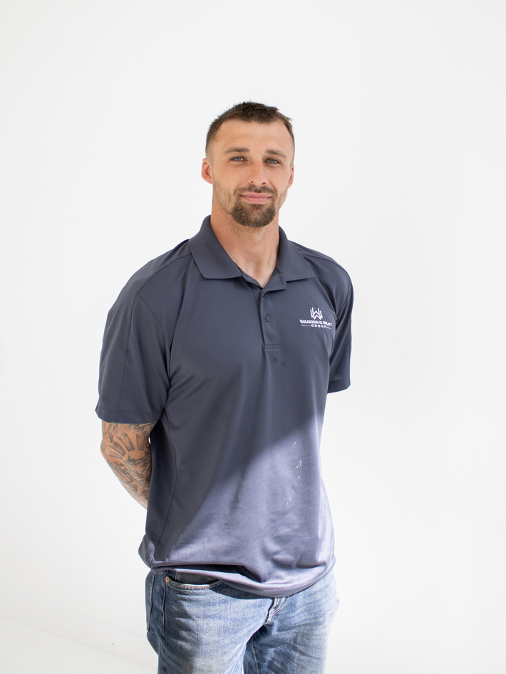 Man wearing a gray polo shirt with a logo on a white background