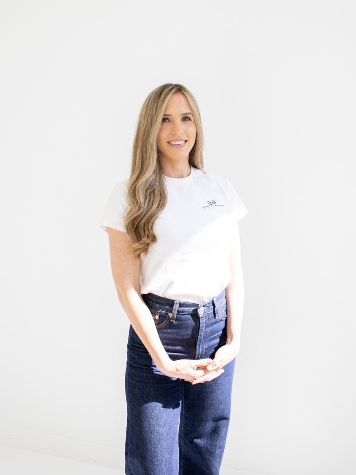 Woman wearing a white t-shirt and blue jeans on a plain background