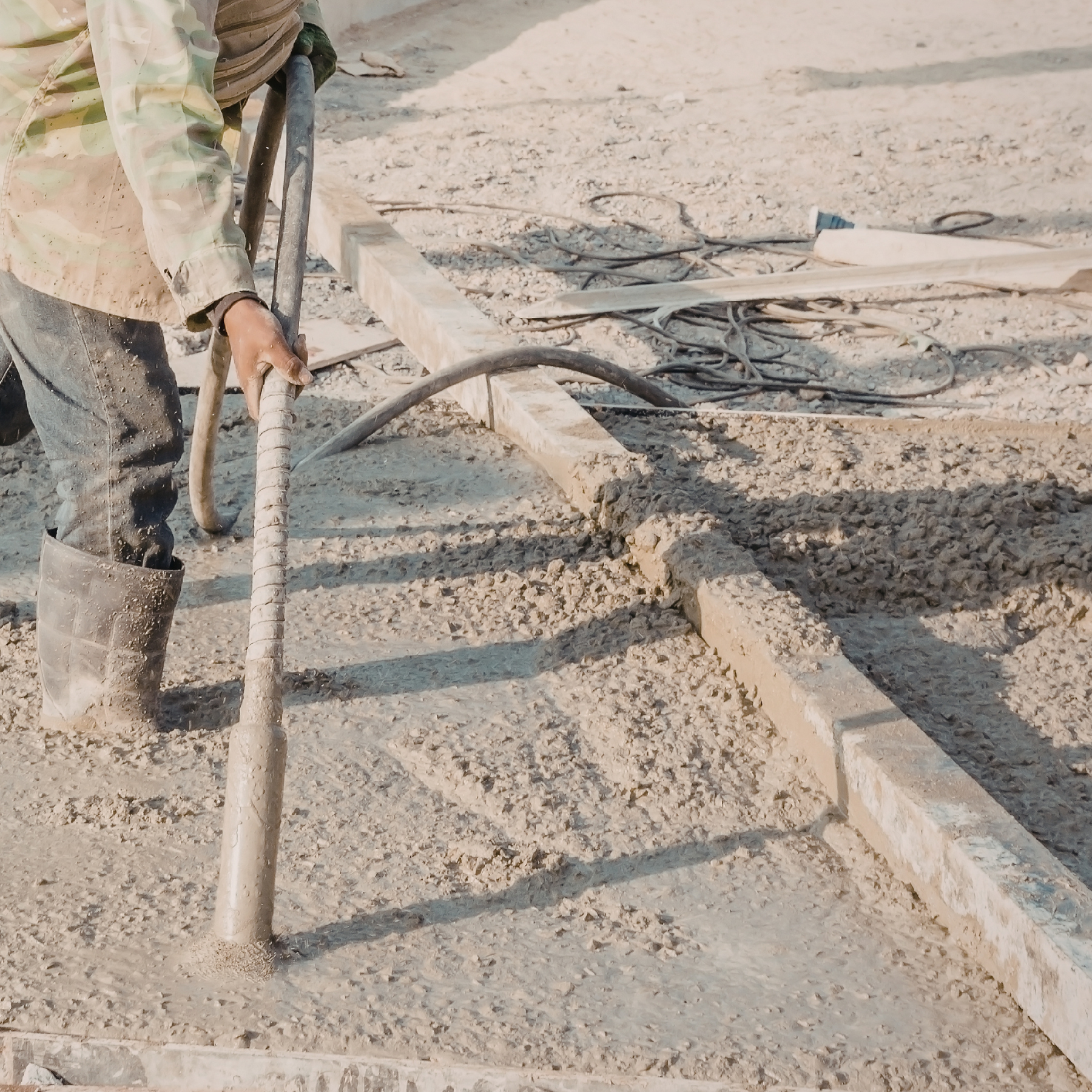 Person using a concrete vibrator on a freshly poured concrete surface