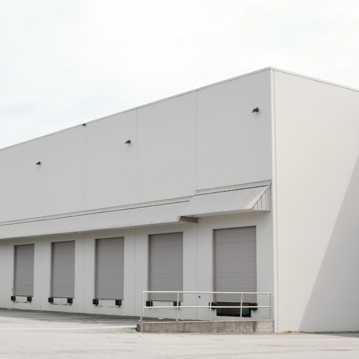 Modern industrial building with white exterior and roller shutters
